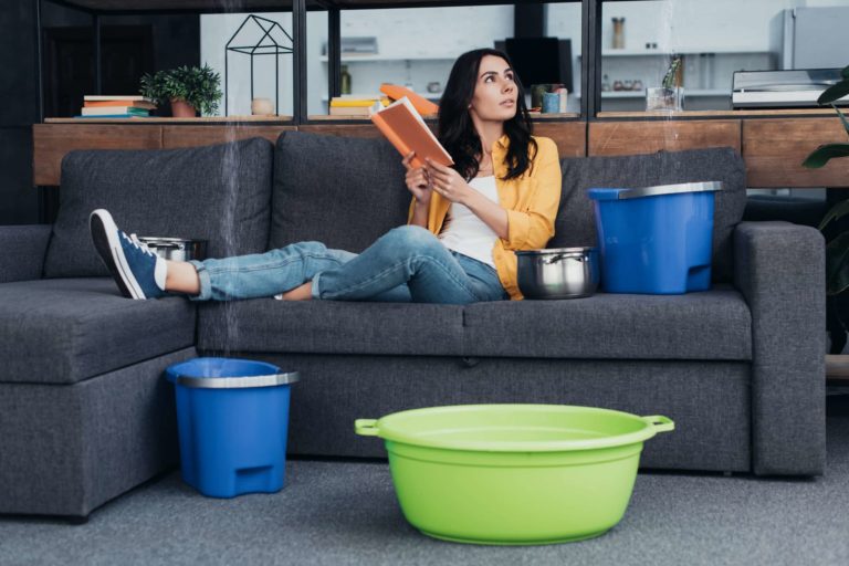 Woman reading book on sofa during water leak in living room Qui est responsable de la vétusté, Exemple de dégât des eaux dû à une infiltration, mauvaise étanchéité